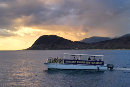 Boat on ocean under scenic sunset with clouds and distant mountains.